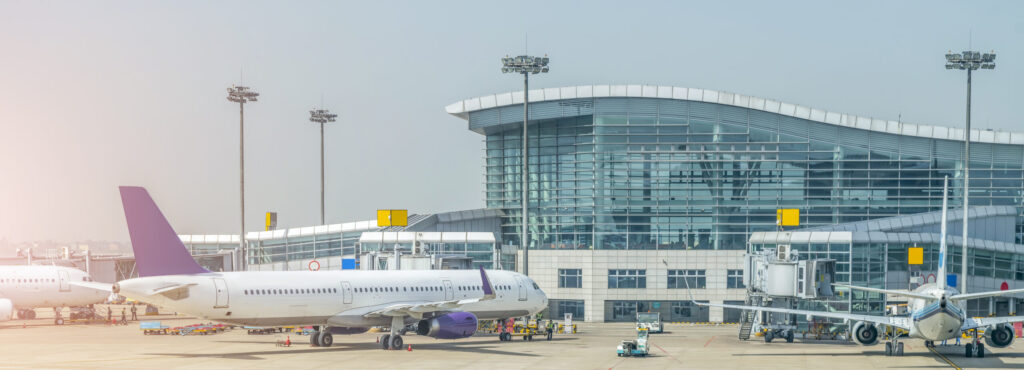 Zwei Flugzeuge stehen vor einem modernen Flughafenterminal auf dem Rollfeld